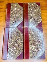 Four half-leather bound books with marbled paper boards and brown leather spines and corners on wood surface.