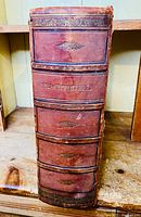 Spine of large brown leather bound Bible embossed with 'Pracht Bijbel' and ornate design