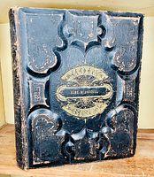 Front cover view showing black embossed leather binding with gold-stamped title and decorative tooling