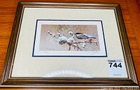 Framed print of 'Early Snow' featuring a bird perched on snow-covered branches in a wood-toned frame under glass.