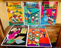 Five vintage Walt Disney comics arranged, featuring Huey, Dewey, Louie, Junior Woodchucks, Daisy, Donald, and Uncle $crooge with colorful covers.