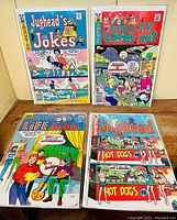 Four Archie series comics bagged and boarded, viewed front covers laid flat, showing vibrant color illustrations and titles: Jughead's Jokes No.60, Archies T.V. Laugh-Out No.60, Life with Archie No.66, Jughead No.243.