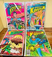 Photo showing four World of Krypton comic books from DC Comics stacked and bagged, colorful covers featuring Superman and Kryptonian imagery.