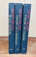 Spine view of three books showing titles and author: Black Spring, Tropic of Capricorn, Tropic of Cancer, all by Henry Miller with Grove Press.