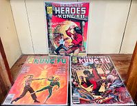 Photo showing three issues of The Deadly Hands of Kung Fu comic books with colorful action covers; arranged on a wood surface against a light wall.