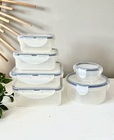 Photo showing the six clear plastic Lock & Lock containers stacked and arranged. The containers have blue silicone seals and white locking lids in rectangular and round shapes.