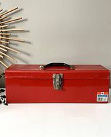 Front view of closed red Mastercraft metal toolbox with latch and black handle, visible wear marks