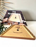 Photo of the lap harp and its box, showing the triangular wooden harp with 12 metal strings and the box titled 'The Music Maker' with promotional text.