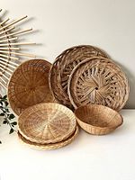 Photo showing set of six wicker baskets with various weaving styles, sizes, and natural tones arranged on white surface.