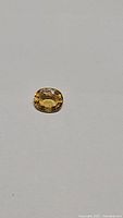 Oval cut deep golden yellow sapphire gemstone photographed on a plain background showing its color, size, and clarity.