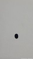 Top view of the deep blue oval cut sapphire on a plain background showing its shape and color.