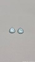 Pair of pear-shaped aquamarine gemstones shown individually on plain white background.