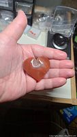 Heart-shaped hand carved agate stone in a person's palm showing overall size and shape.