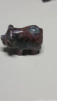 Front side view of the hand carved natural gemstone pig figurine showing its shape, colors, and polished surface.