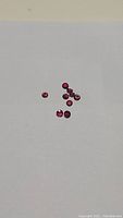 Ten round red rubies scattered on white background