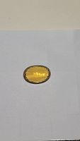 Oval cut 28.3 carat golden citrine gemstone placed on white background showing color and cut detail.