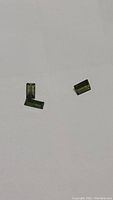 Three natural green tourmaline stones, baguette cut, displayed on white background to show clarity and color.