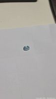 Oval cut natural aquamarine gemstone displayed on white background showing size and color.