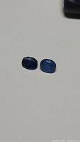Two oval cut kyanite gemstones in royal blue and cornflower blue colors placed on a plain surface to show color and shape