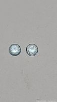 Close-up of two round cut natural sky blue topaz gemstones on grey background