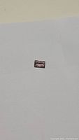 Rectangular baguette cut peach tourmaline gemstone on a plain background, showing color and cut.