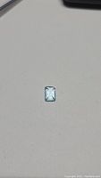Photo of the natural sky blue topaz gemstone with emerald cut, showing clear sky blue color and high clarity from the top view.