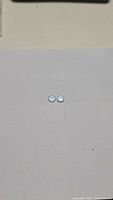 Two round cut natural sky blue topaz gemstones on a white background.