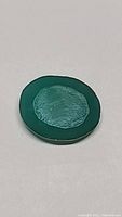 Close up photo of an oval cut vivid green onyx gemstone showing a polished surface and glowing effect under light.