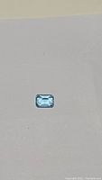 Top view of the natural Swiss blue topaz emerald cut gemstone showing its rectangular shape and blue color.