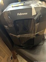 Front view of the black Fellowes paper shredder showing the brand name and taped exterior.