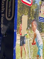 Box showing children playing with Little Tykes Splash Face water toy, kids spraying water and smiling outdoors.