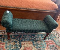 Front view of hunter green fabric bench placed on a patterned rug, showing overall shape and condition.
