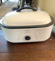 Full view of the white Rival electric roaster oven with black handle and temperature control knob on front