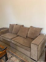Full view of large 2-cushion brown corduroy sofa with four back cushions placed against a wall.