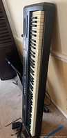 Side angle view of Williams Allegro digital piano with foot pedal and power cords visible