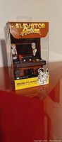 Front and top view of the mini arcade game in box showing Elevator Action branding and characters on box.