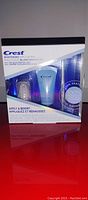Front view of sealed Crest Whitening Emulsions kit showing whitening emulsions tube, LED light, and applicator wand.