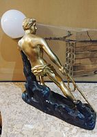 Side view of gold warrior sculpture with lamp globe on textured dark bronze base