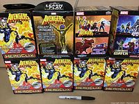 Photo of eight boxed large Marvel Avengers Heroclix colossal gaming figures, showing front and sides of packaging with branding, character art, and collectible claims.