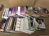 Large assortment of hockey cards in multiple stacks showing various players and card designs.