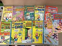 Photo of 11 Richie Rich comic books laid out side by side showing colorful front covers with various themes.