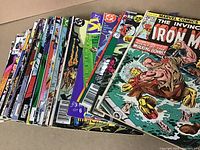 Photo showing a spread of comic books featuring Marvel and DC superhero titles including The Invincible Iron Man, Doctor Strange, The Warriors, Captain Atom, Deathlok, Guardians of the Galaxy, and Skreemer.