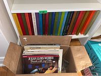Box filled with assorted classical music vinyl LP records visible, including one titled 'Travels with my Cello' by Julian Lloyd Webber with record label Philips.