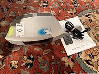 Main unit on patterned rug alongside remote, power cord and manual