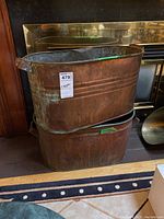 Two stacked large copper basins showing tarnished exterior surfaces and patina.