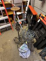 Wide shot showing overall lot contents including tall candle holder, baskets, pedestals and trays in storage area