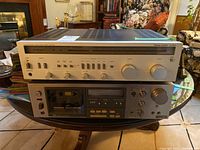 Stacked Harman Kardon HK460i receiver on top of Sony TC-K61 cassette deck on wooden table.