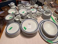 Overview of plates, bowls, cups, saucers, teapot, jug and other serving pieces laid out on table