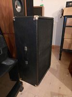 Front and side view of black box speaker with metal corner protectors and side handle