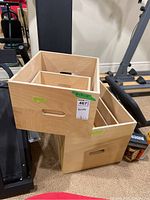 Three plywood step-up boxes nested and stacked on fitness equipment